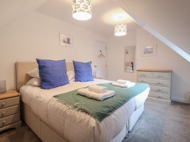 A bedroom with a bed and dresser at Corner Cottage, Thorpeness