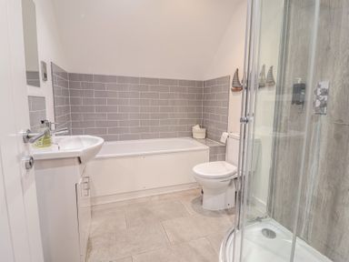 A bathroom with a sink, bathtub, toilet, and shower at Corner Cottage, Thorpeness