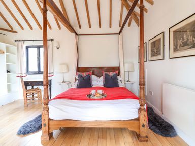 A bedroom with a four-poster bed and chair at Fishpond House, Sotherton