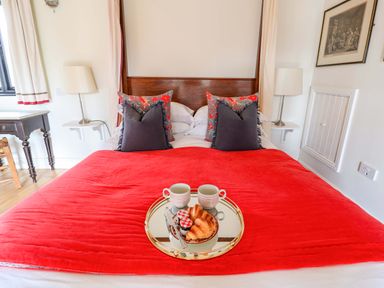 A bedroom with a red blanket and breakfast items at Fishpond House, Sotherton