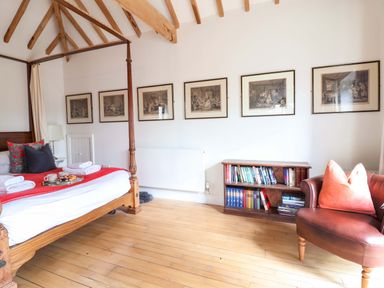 A bedroom with a four-poster bed and shelves of books at Fishpond House, Sotherton