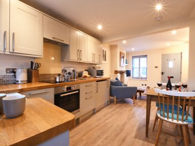 A kitchen and dining area with wooden countertops and a table with wine glasses at Smugglers Rest Aldeburgh
