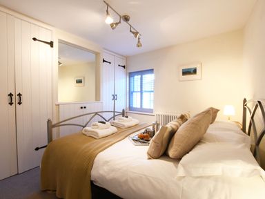 A bedroom with a bed made with towels and breakfast tray by the window at Smugglers Rest Aldeburgh