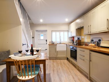 A kitchen with wooden countertops a dining table with wine glasses and a bottle at Smugglers Rest Aldeburgh