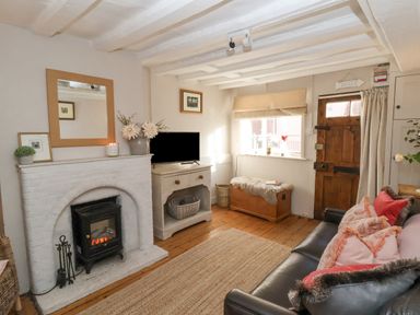 A living room with a white brick fireplace a wooden chest and a leather sofa at Rosemary Cottage Aldeburgh