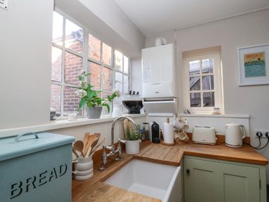 A kitchen corner with a sink wooden countertop appliances and kitchen utensils at Rosemary Cottage Aldeburgh