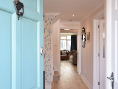 A hallway with wooden flooring leading to a living room with sofas at Napier House Southwold
