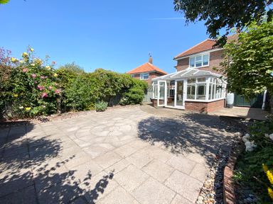 An outdoor patio area with paving stones plants and flowers next to a house with a conservatory at Napier House Southwold