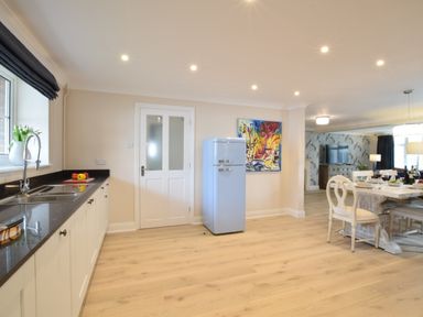 A kitchen with white cabinets a black countertop and a blue refrigerator next to a dining area at Napier House Southwold