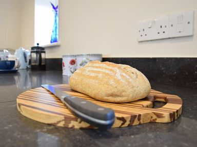A loaf of bread and a knife on a wooden cutting board in a kitchen at Napier House Southwold