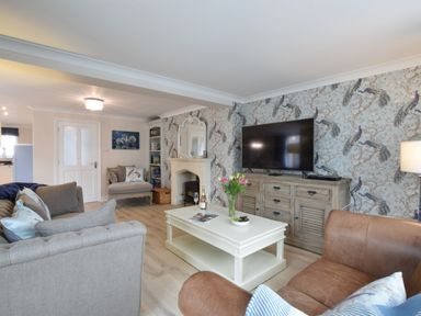 A living room with a sofa chair armchair coffee table television and fireplace at Napier House Southwold