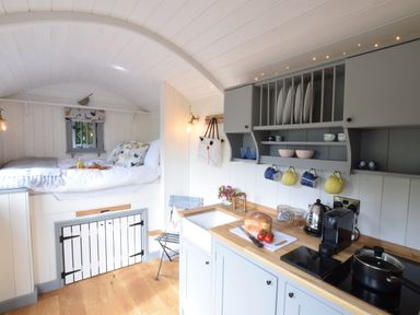 A small kitchen and sleeping area with bed pillows and kitchen utensils at Shepherds Pightle in Hollesley