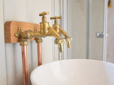 A close up of brass taps with water flowing into a white basin at Shepherds Pightle in Hollesley
