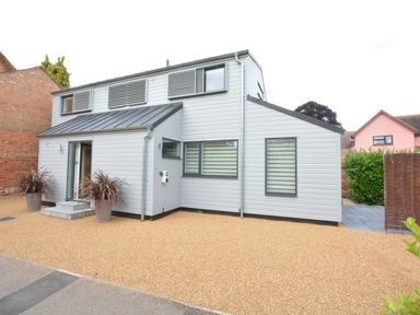 A modern two-story house with gray siding and gravel driveway at Bramertons Nest Long Melford