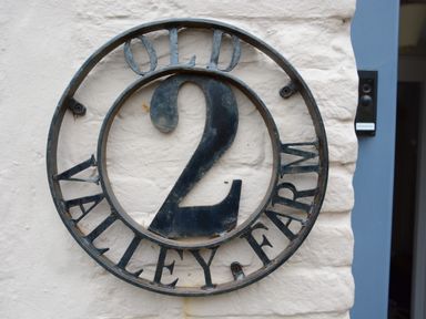 A metal house number 2 sign on a white wall at Old Valley Farm Walberswick