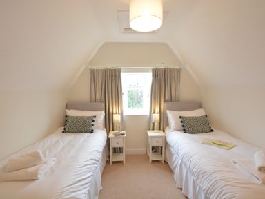 A bedroom with two single beds two bedside tables and a window at Old Valley Farm in Walberswick