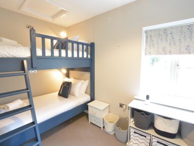 A bedroom with blue bunk beds white drawers and baskets near a window at Old Valley Farm in Walberswick