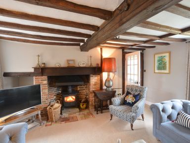 A living room with a brick fireplace a patterned armchair and a blue sofa at Old Valley Farm Walberswick