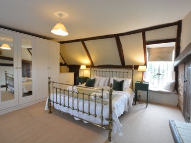 A bedroom with a metal bed frame white wardrobes bedside tables and a window seat at Old Valley Farm Walberswick