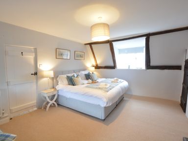 A bedroom with a double bed bedside tables lamps and a window with wooden beams at Old Valley Farm in Walberswick