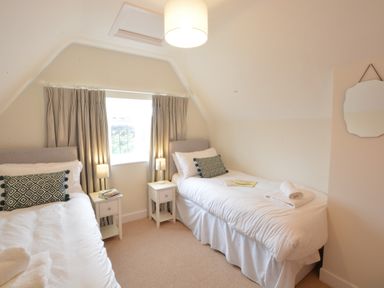 A bedroom with two single beds bedside tables lamps and a window at Old Valley Farm Walberswick