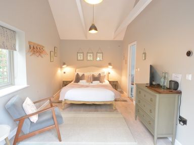 A bedroom with a double bed armchair dresser and bedside tables at Old Valley Farm in Walberswick