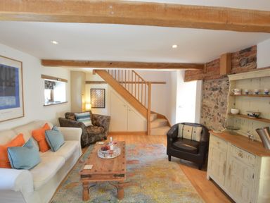 A living room with a sofa and armchairs a wooden coffee table a rug and a cabinet May Barn Ixworth Bury St Edmunds