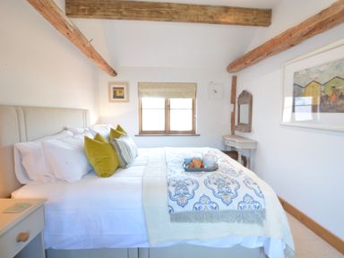 A bedroom with a bed cushions and a tray with breakfast by a window at May Barn Ixworth in Bury St Edmunds