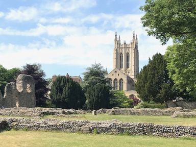 A stone wall with trees and a church tower in the background at May Barn Ixworth