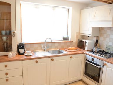 A kitchen with a sink oven stove microwave coffee maker and bread on a cutting board at May Barn Ixworth in Bury St Edmunds