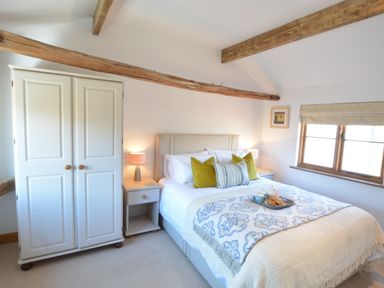 A bedroom with a double bed bedside tables and wardrobe at May Barn Ixworth in Bury St Edmunds