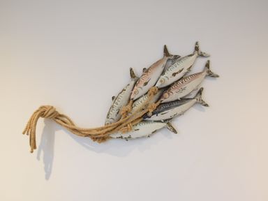 A wall decoration of a cluster of six fish tied together with rope at The Smokehouse Cottage in Southwold