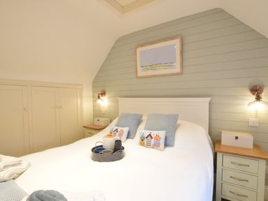 A bedroom with a white bed two bedside tables and wall lights at The Smokehouse Cottage in Southwold