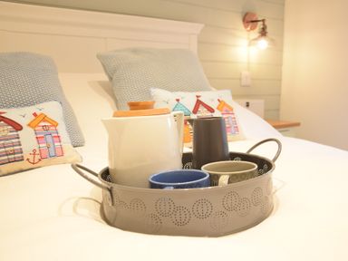 A bed with pillows and a tray holding a teapot and cups at The Smokehouse Cottage in Southwold