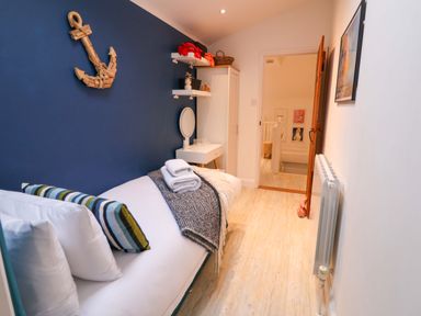 A bedroom with a single bed and a mirror at The Smokehouse Cottage in Southwold