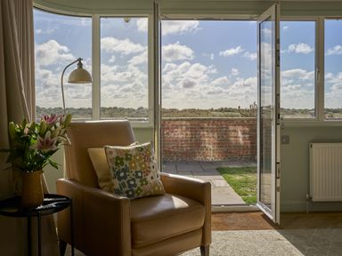 A living room with a chair and flowers at Harbour Lights in Southwold