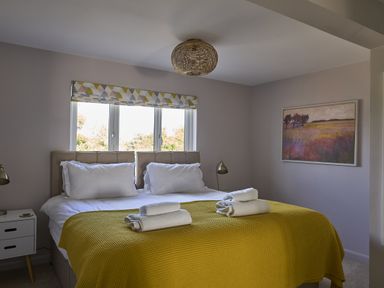 A bedroom with a double bed and windows at Harbour Lights in Southwold