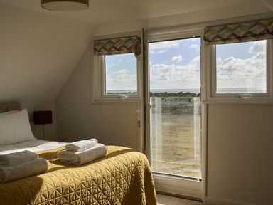A bedroom with a bed and towels at Harbour Lights in Southwold
