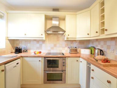 A kitchen with wooden countertops and cream cabinets with various appliances on the counters at Bluebelle Cottage Peasenhall