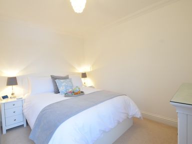 A bedroom with a bed with pillows and a tray with a teapot and cups on it with bedside tables and lamps at Bluebelle Cottage Peasenhall