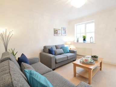 A living room with two grey sofas and a wooden coffee table by a window at Bluebelle Cottage Peasenhall