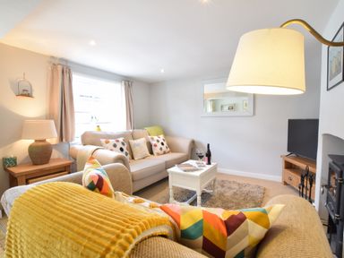 A living room with two sofas a coffee table a lamp and a television at Satis Cottage Westleton