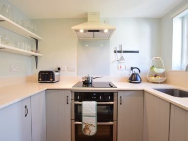 A kitchen with a stove oven toaster kettle and fruit basket at Satis Cottage Westleton