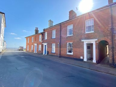 A street with brick houses and a van near the waterfront at Albion House Southwold