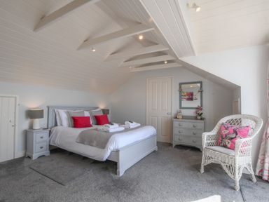 A bedroom with a double bed bedside table dresser and chair at Albion House Southwold