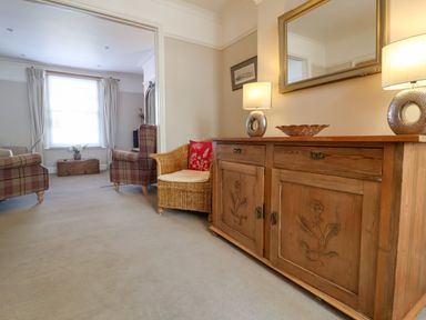 A living room with wooden sideboard chairs and a window at Albion House Southwold