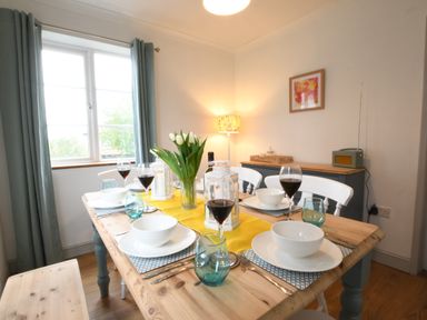 A dining room with a wooden table set with bowls wine glasses and tulips at Rosedene Rickinghall