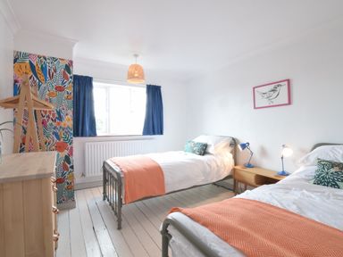 A bedroom with two single beds and orange throws at Rosedene Rickinghall