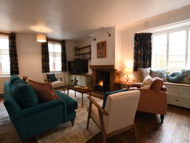 A living room with sofas chairs a coffee table a fireplace and a television at Rosedene Rickinghall