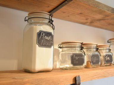 Glass jars on a wooden shelf labeled plain flour peppermint tea coffee and tea at Rosedene Rickinghall